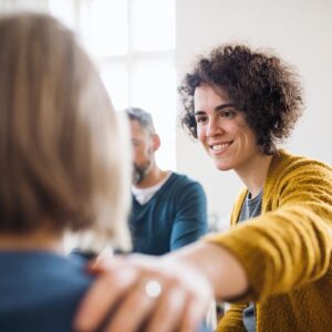 woman offering support to another woman in group therapy