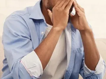 man with glasses holding his eyes like he's worried