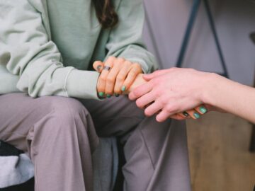 two women holding hands in psychotherapy